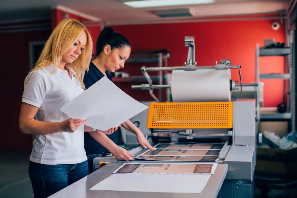 Two women reviewing physical print samples for overseas printing