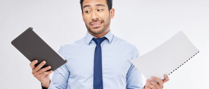 Man holding an ipad (digital) and a hardcopy booklet (print)