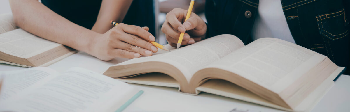 University students studying and pointing in a textbook.