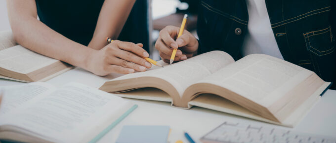 University students studying and pointing in a textbook.